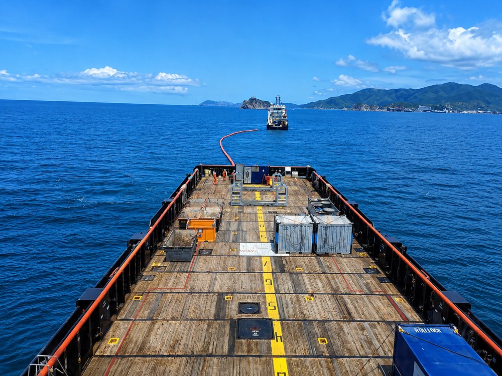 Vessel deck underway with coastline in the distance